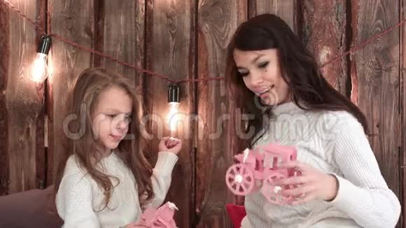 年轻的母亲和她的女儿在圣诞前夜快乐地玩玩具视频的预览图