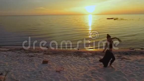 美丽的女人在夕阳下的沙滩上跳舞视频的预览图