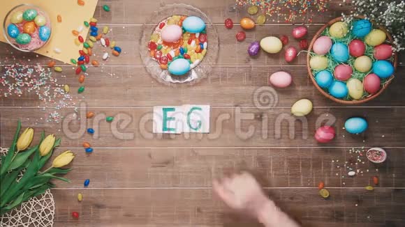 人类把文字猎蛋放在装饰着复活节彩蛋的桌子上顶部视图视频的预览图