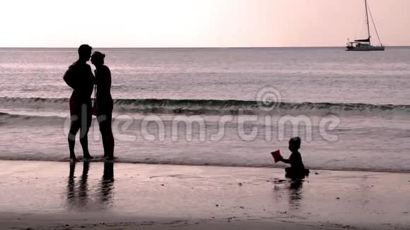 幸福的家庭和一个孩子在海滩度假日落时分慢动作1920x1080视频的预览图