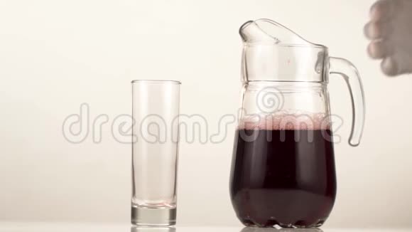 那人的手拿着装饰器把红色的果汁倒进玻璃杯里视频的预览图