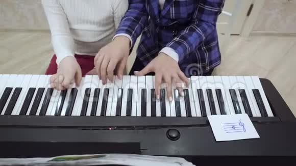 从小女孩在电钢琴上弹奏的老师的俯视图视频的预览图