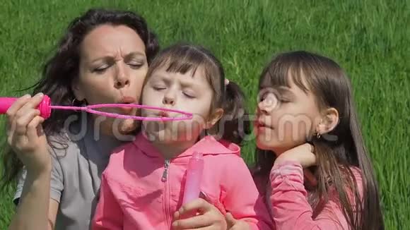 妈妈和女儿吹泡泡公园里的家人和妈妈在一起的孩子在玩泡泡视频的预览图
