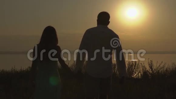 幸福的一对夫妇在夕阳下的海边漫步爱的概念视频的预览图