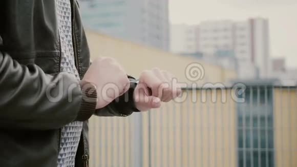 男人用他的智能手表触摸屏站在屋顶上然后走开双手特写4k视频的预览图