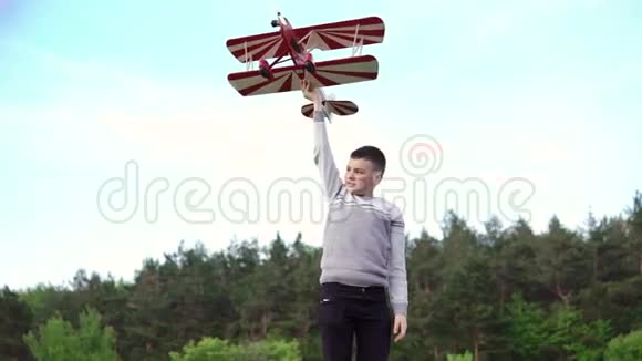 英俊的男孩举起玩具飞机在绿色的斜坡上4k视频的预览图
