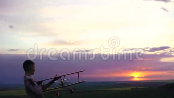男孩用玩具飞机在村庄上空的青山上4K视频的预览图