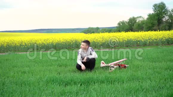 坐在绿色小麦上的玩具飞机男孩4k视频的预览图