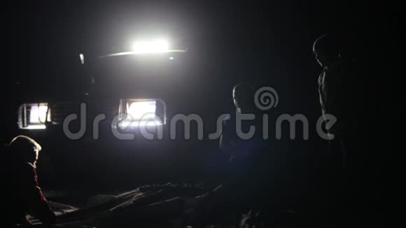 两名成年男子和儿童从越野车上搭帐篷的夜间镜头视频的预览图