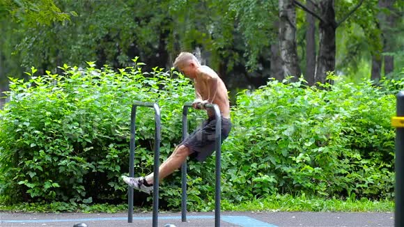 在城市公园的酒吧里做俯卧撑的运动员侧视健身视频的预览图