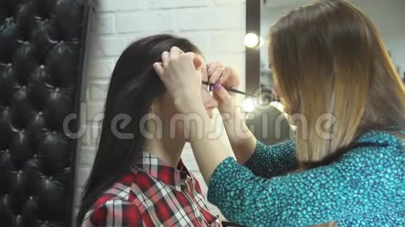 一位年轻的女化妆师在美容院做美容美丽的黑发女孩视频的预览图