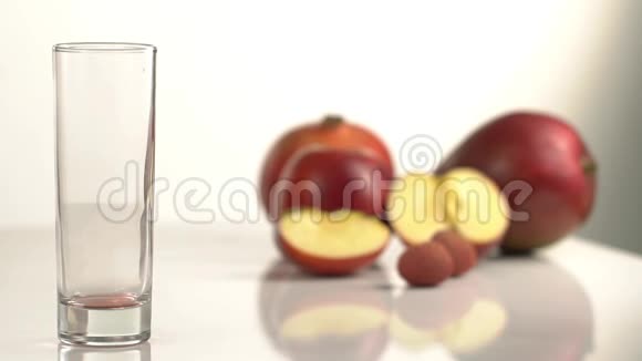 在苹果模糊的背景下空玻璃的特写镜头充满了红色的果汁视频的预览图