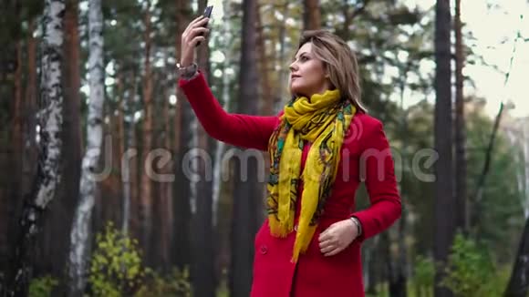 穿着红色外套的年轻女子沿着秋天的公园散步美丽的女孩享受温暖的秋天下午视频的预览图