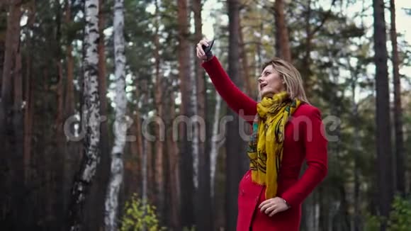 穿着红色外套的年轻女子沿着秋天的公园散步美丽的女孩享受着温暖的秋天下午视频的预览图