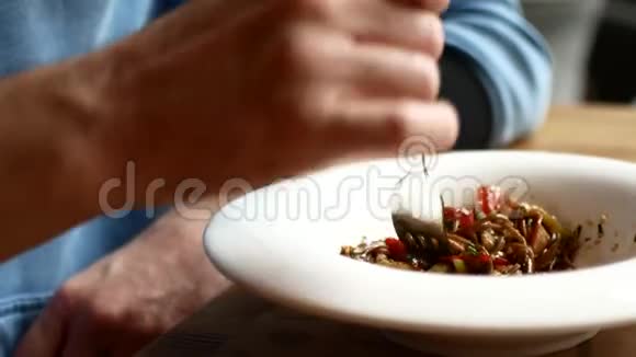 一个男人用叉子吃亚洲面条和蔬菜视频的预览图
