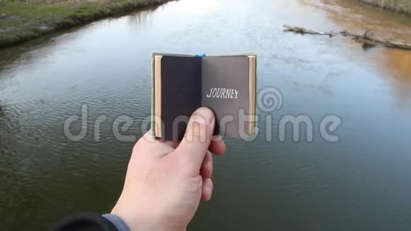 旅程旅行者旅行度假参观想法旅行者拿着一本有文字的书在美丽的河流的背景上视频的预览图
