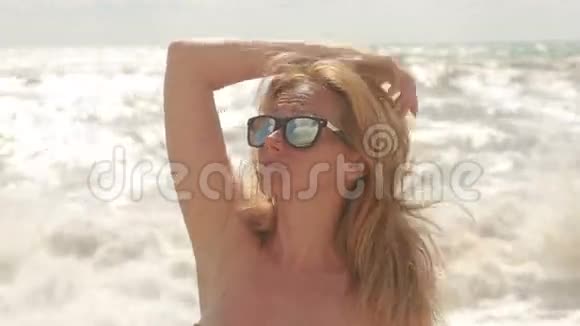 戴太阳镜的漂亮年轻女人在大海的背景下视频的预览图