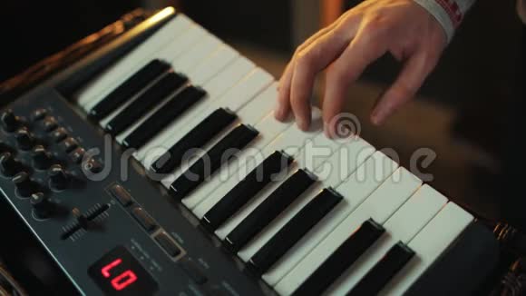 穿着kosovorotka衬衫的男性手快速敲击MIDI控制器键盘的键视频的预览图