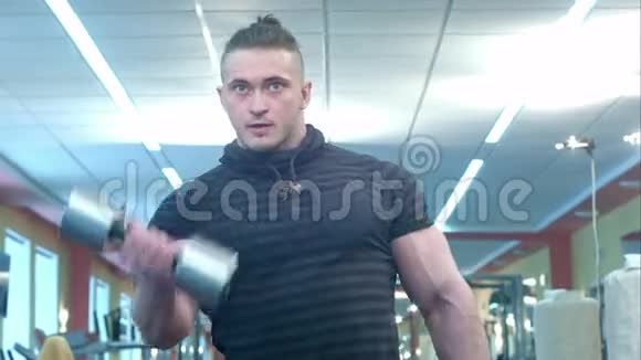 强壮的运动员在健身房里用哑铃做二头肌锻炼视频的预览图