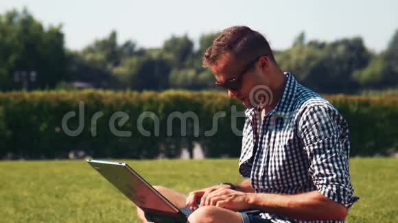 戴墨镜的男人在公园用电脑视频的预览图