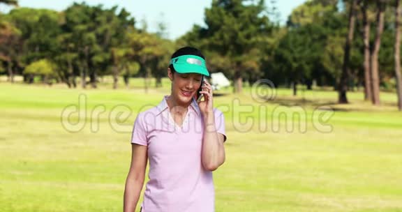 女高尔夫球手在打高尔夫球时用手机说话视频的预览图