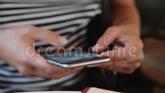 关闭女孩使用智能手机在咖啡馆户外短信手机手拿手机视频的预览图