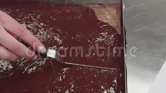 糕点厨师女手将融化的巧克力撒在烤盘里视频的预览图