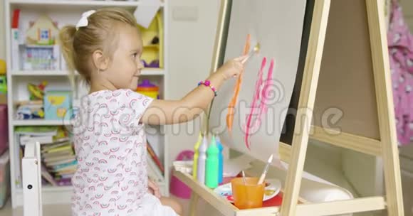 可爱的金发小女孩画着水彩视频的预览图