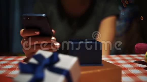 在一个蓝色的秘密礼物盒附近用智能手机关闭女性视频的预览图