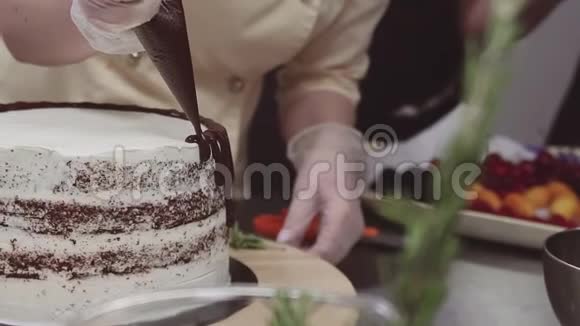 女糕点厨师用融化的片装饰海绵蛋糕视频的预览图