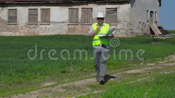 建筑检查员在草地上的旧废弃房屋附近写信视频的预览图