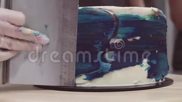糕点厨师用刮饼机用手抚平蓝彩锦缎视频的预览图