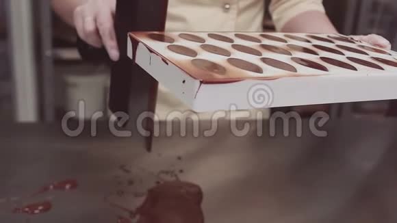 糕点厨师刮掉过多的巧克力塑料模具视频的预览图