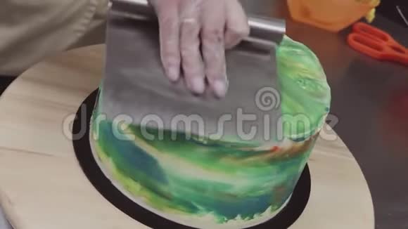 糕点刮饼机用手抚平蛋糕上绿油油的糖霜视频的预览图