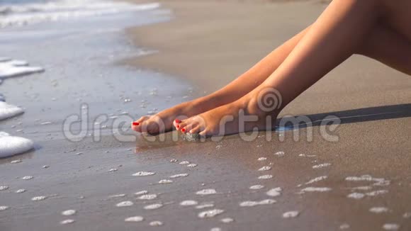 海水冲刷着晒黑的雌性脚美丽的年轻女子在暑假期间在海岸放松女孩的腿视频的预览图