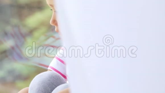 坐在窗台上的可爱小女孩双手并拢视频的预览图
