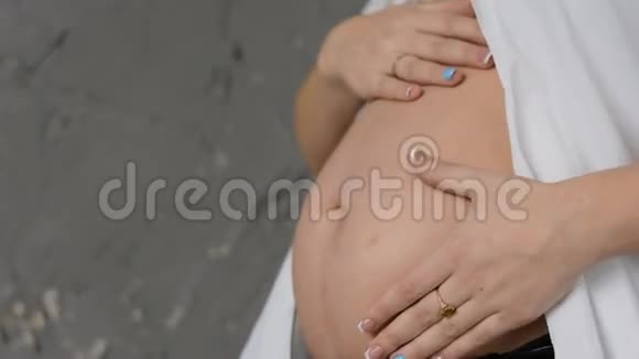 穿白色衬衫的快乐孕妇小心地拥抱你的肚子慢动作视频的预览图