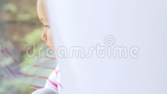 坐在窗台上的可爱小女孩双手并拢视频的预览图