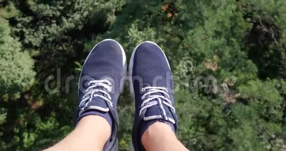空中POV视图飞过美丽的森林树木空中相机拍摄和人的腿与蓝色运动鞋的框架视频的预览图