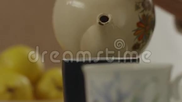 女人把热绿茶倒进杯子里把不同种类的草药倒在木桌上女性倒茶的侧景视频的预览图