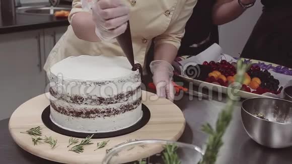 女性糖果师用融化的巧克力装饰海绵蛋糕视频的预览图