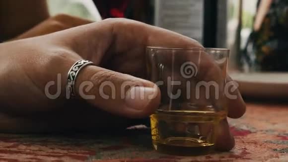 戴眼镜的胡子男在露台上喝干邑酒精短杯加油视频的预览图