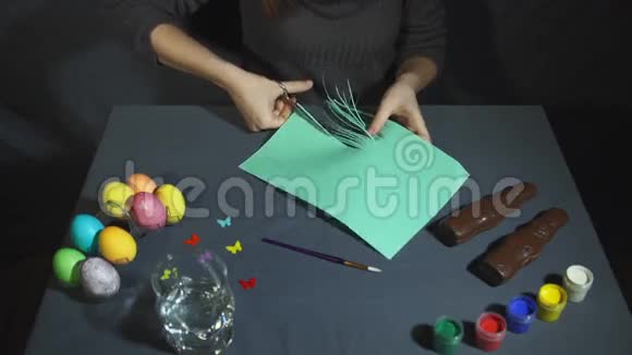 女性的手在灰色的桌子上用剪刀剪成薄薄的条纹视频的预览图