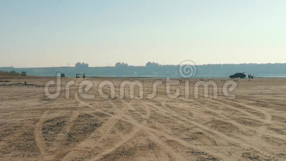 三个骑摩托车的人骑在沙滩附近的沙漠从很远骑自行车视频的预览图