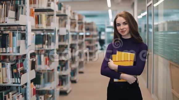 长发女孩站在图书馆的书架前微笑视频的预览图