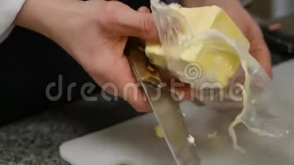厨师切一大块黄油做准备蛋糕用刀子切黄油视频的预览图