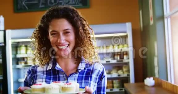 微笑的女人在超市拿着一盘杯子蛋糕的画像视频的预览图