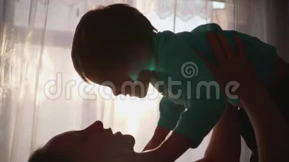母亲双手抱着一个小孩子阳光透过窗户宝宝的欢声笑语视频的预览图