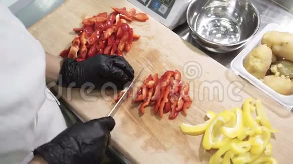 厨师在工业厨房的桌子上切条红椒视频的预览图