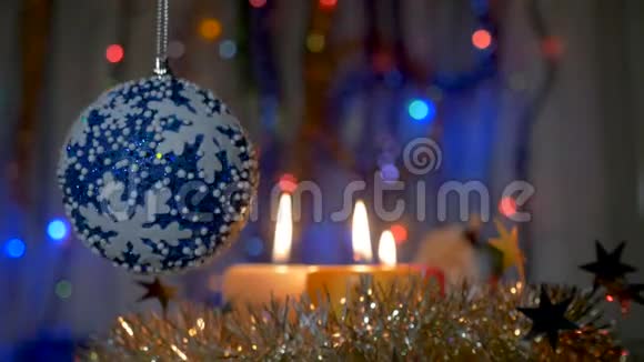 一个大蓝球挂在圣诞树上新年和圣诞装饰品燃烧蜡烛燃烧的视频的预览图